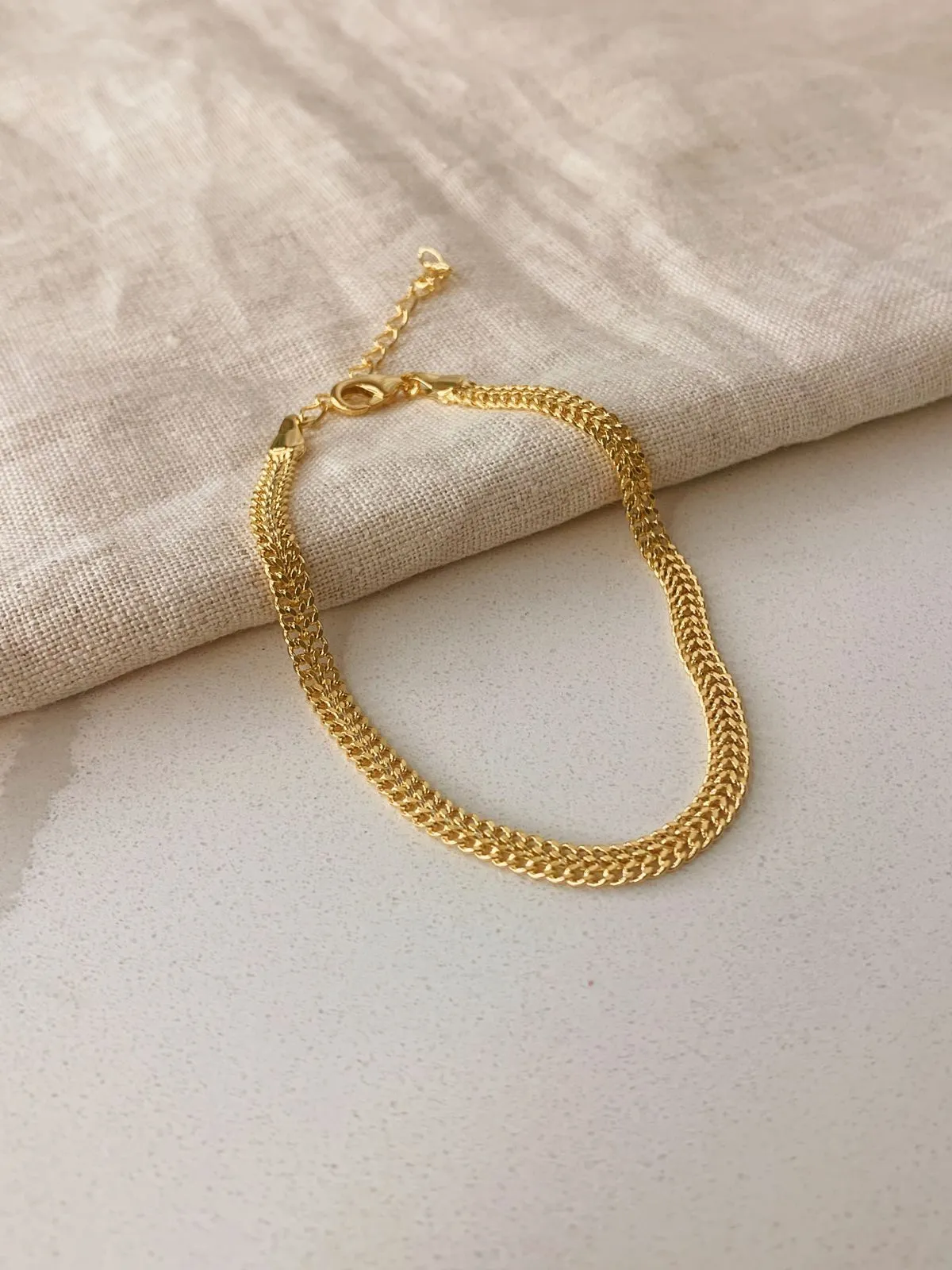 PULSEIRA MALHA TRABALHADA. 20,5CM DE COMPRIMENTO E 5CM DE REGULAGEM. BANHADA A OURO 18K.