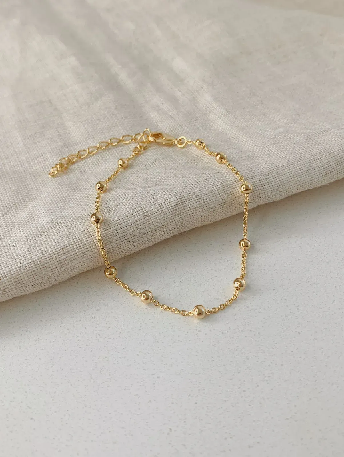 PULSEIRA 11 BOLINHAS. 17CM DE COMPRIMENTO E 5CM DE REGULAGEM. BANHADA A OURO 18K.