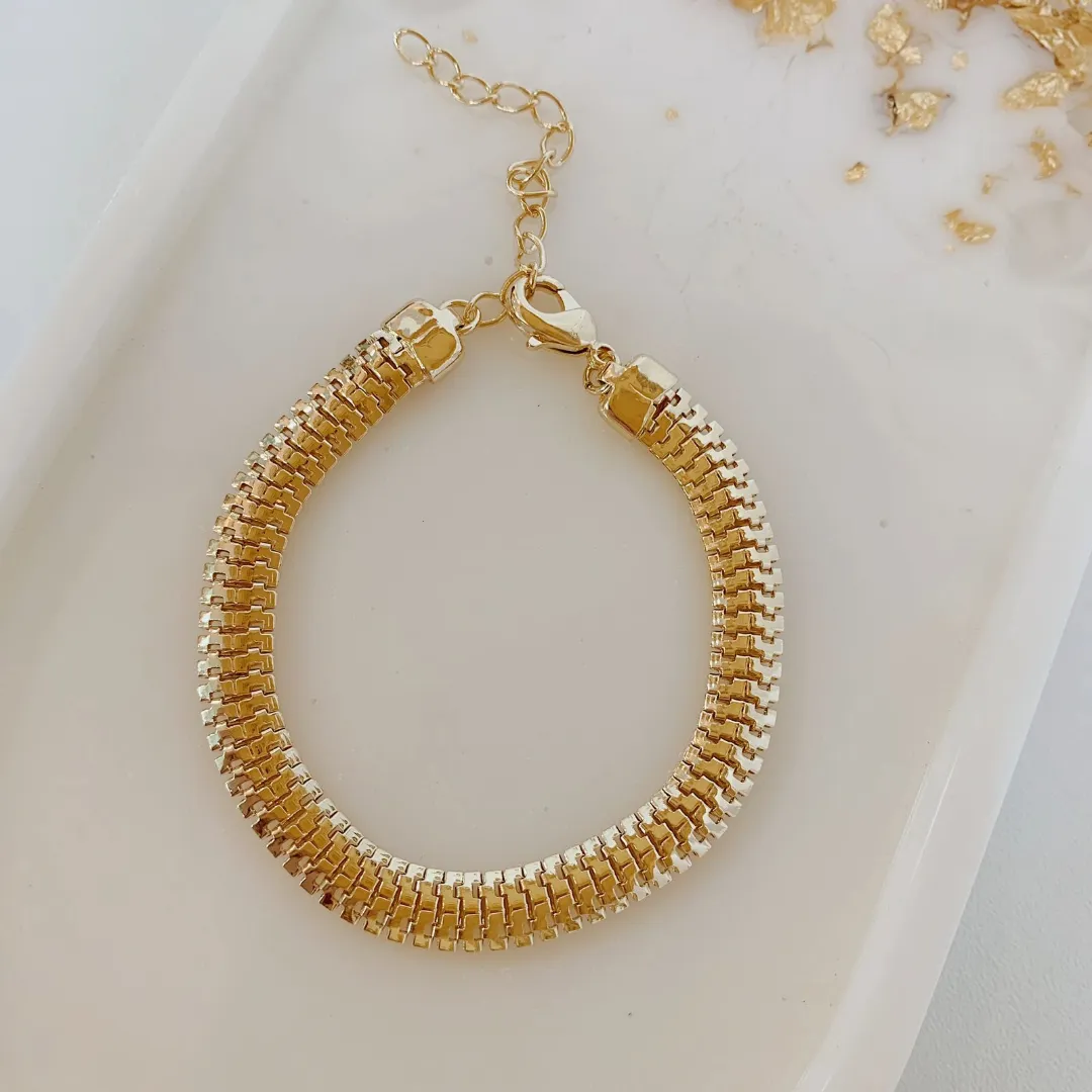 PULSEIRA MALHA VAZADA. 6MM DE ESPESSURA. 15CM DE COMPRIMENTO E 5CM DE REGULAGEM. BANHADO A OURO 18K.