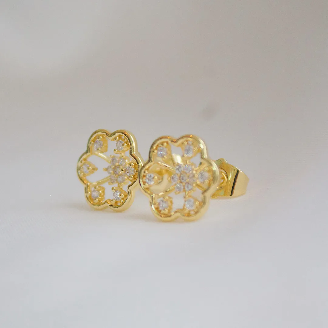 BRINCO FLOR VAZADA COM DETALHES EM ZIRCÔNIA. BANHADO A OURO 18K.