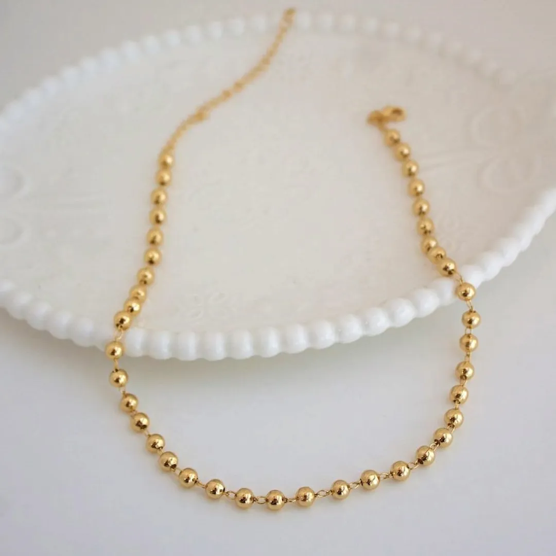 CHOKER ESFERAS. 35CM DE COMPRIMENTO E 10CM DE REGULAGEM. BANHADA A OURO 18K.